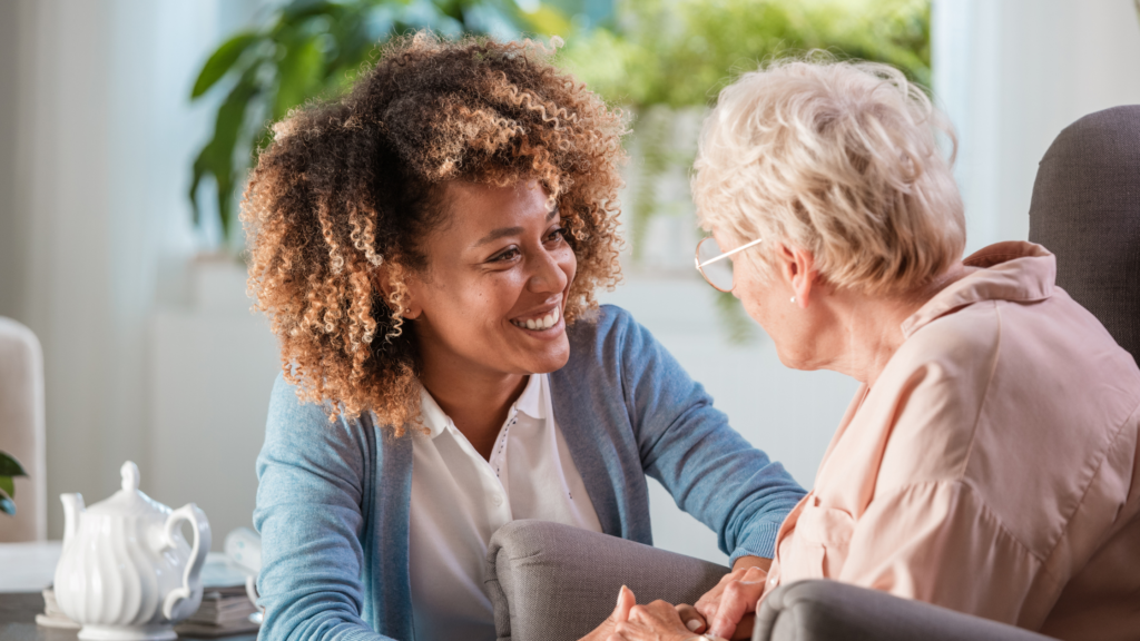 young woman holding hands with an elderly woman in a care home