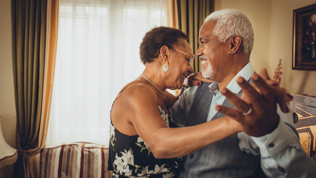 reminiscence therapy can stimulate each of the senses, like hearing through old music as seen here with an older black couple dancing together happily