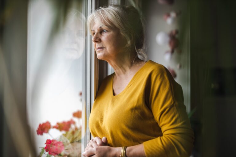 older woman looking out of the window contemplating how to manage feelings of anxiety in dementia